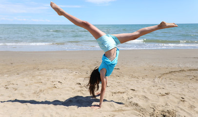 girl does gymnastics on the beach with a pirouette