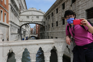 tourist takes a selfie with the Bridge of Sighs behind him