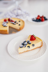 Piece of homemade Christmas winter berry cheesecake on a white plate.