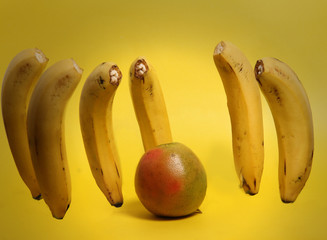 bananas acosando a una naranja sobre fondo amarillo