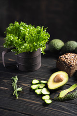 Fresh green vegetables and loaf of rye bread placed on wooden rustic table