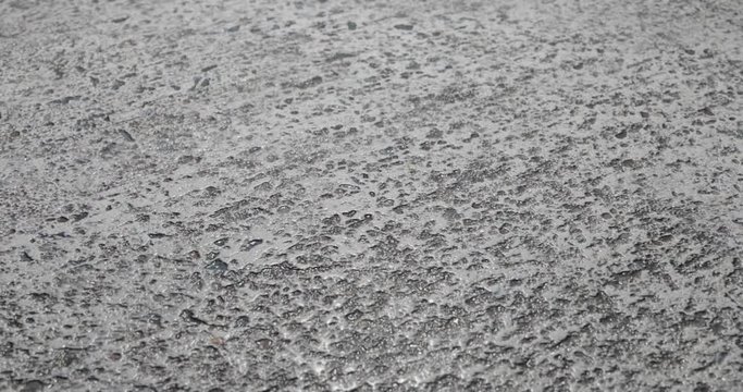 Hard concrete asphalt pavement road surface. Zoom closeup scene while camera smoothly and stabilized filming textured surface macro shot. 