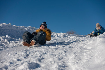Fototapeta na wymiar happy boy sliding down snow hill on sled outdoors in winter, sledging and season concept