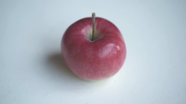 Red apple rotate on white table. Loopable moving image.