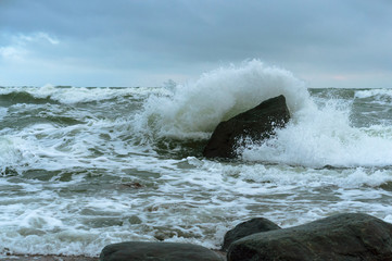 The waves crash on the rocks. Sea coast. Waves and storms at sea. Rocky shore.