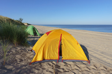 Tourist tents on the sea coast. Tourist tents in the morning sun. Campground at dawn.