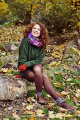 jeune et jolie femme rousse dans un parc arboré en automne avec des feuilles mortes