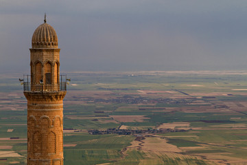 Minaret of the Great Mosque, known also as Ulu Mosque, with the Mesopotamia plain and Syrian border on the background, in Mardin, Turkey