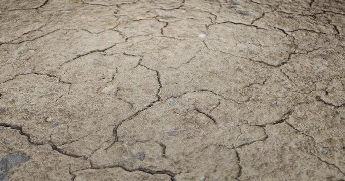 Dry cracked soil at drought ground desert land. Zoom closeup scene while camera smoothly and stabilized filming textured surface macro shot. 