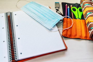 School elements for the beginning of the course with a surgical mask focused on the new normality of covid-19. Notebook and colored pencils for the school. Selective approach