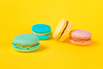 Sweet almond colorful unicorn pink blue yellow green macaron or macaroon dessert cake isolated on trendy yellow modern fashion background. French sweet cookie. Minimal food bakery concept Copy space