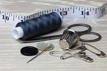 Supplies and equipment for sewing on a wood work surface cotton tape measure scissors thimble needle pins buttons