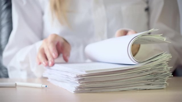 Businesswoman signing a contracts, legal agreements, papers. Business woman in white shirt sitting in her workplace in office, signing a many documents. Closeup shot, close up, Sign documents concept