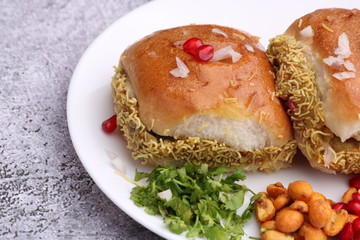 Dabeli is an Indian snack item served with Pomegranate Seeds and Cilantro in white ceramic plate. It's a popular Navratri Festival food