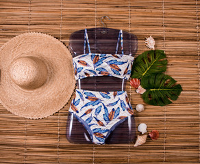 Biquíni Hot Pants moda praia, esteira de palha de fundo, com chapéu de palha do lado 