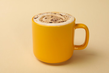 Yellow cup of latte on beige background