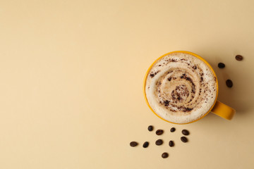Cup of latte and coffee seeds on beige background