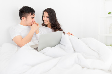 Obraz na płótnie Canvas asian lover rest on bed, asian man holding hand and kiss hand of wife in bedroom, they feeling love and happy together, hands in hands, happiness honeymoon and valentine's day