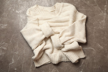 Knitted sweater on gray background, top view