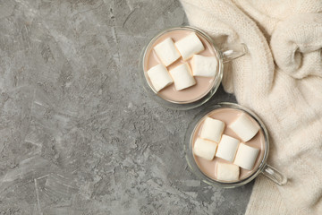 Sweater and cups of coffee with marshmallows on gray background