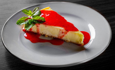 Strawberry cheesecake served on white plate on black wooden table background