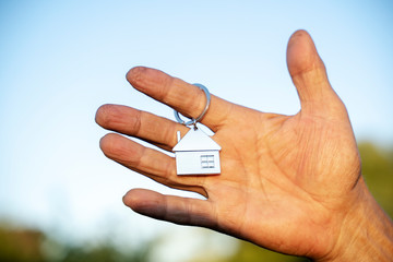 key chain in the form of a house in your hand of buying a home