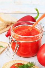 Ajvar, pepper mousse in a jar and on gray plate with bread and gray backgground