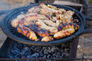 Pieces of meat and sausages on the grill with fire.