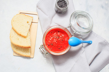 Ajvar, pepper mousse in a jar and on bread and blue spoon on backgground