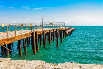 Very old pier on the Black Sea. Closed for work. The supports rust and gradually collapse from seawater. Yevpatoriya, Crimea.