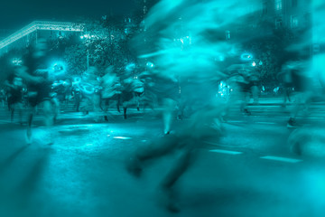 Silhouettes of a group of runners on the city road, illumination, abstract, motion blur, night festival. Concept of a modern lifestyle, healthy lifestyle, green background.