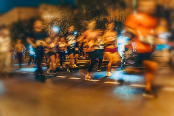 Large group of running athletes on street, night city marathon, blur effect, unrecognizable peole....