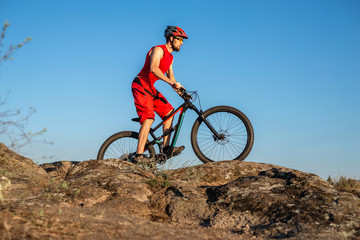 A cyclist rides over stones against a blue sky, copy of the free space.