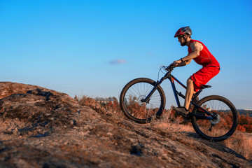 A cyclist rides over stones on a mountain bike, against a blue sky, copy of the free space.