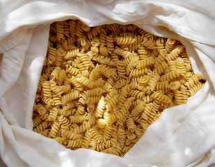 Spiral yellow pasta in a white fabric bag