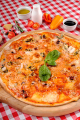 Pizza with seafood, mozzarella, mussels, octopus, squid, salmon, shrimp, cheeseand, fresh rucola and tomatoes sauce, served on a wooden board for a dinner in italian restaurant background, top view. 