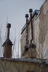 three rusty thin pipes on the roof against a gray overcast sky