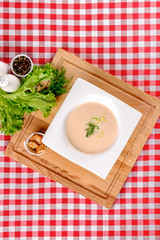 A bowl of creamy potato soup with crackers bread on white plate in italian restaurant background, top view. Vegetable cream soup. Italy food. Close up. space