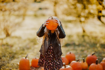 Girl posing with red pumpkin on a pumpkin's field. Focus is at the pumpkin.