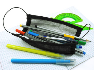 Back to school. School supplies in black handmade protective mask made of fabric and gauze on open...
