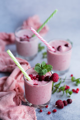 Glasses of berry smoothie on light background.