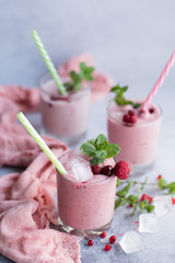 Glasses of berry smoothie on light background.