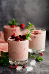 Glasses of berry smoothie with fresh mint on dark background.