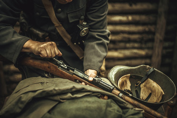 A soldier in a world war II uniform reloads the bolt in a rifle