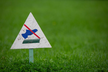 Signpost on the lawn does not walk on a background of lush green grass. close-up. copy space