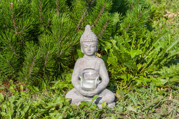 Buddha statue on the natural background. Sunny morning in the park.  Summer background for meditation and relaxation. 