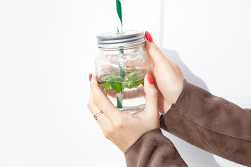 Girl holding in his hand a glass Cup with a straw. On white background. Eco-friendly concept