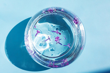 Lilac flowers float in the water. Purple and pink flowers in a glass vase. On a blue background