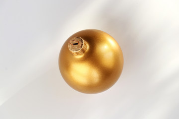 Gold Christmas ball on a white background with shadows. Close-up. Isolated.