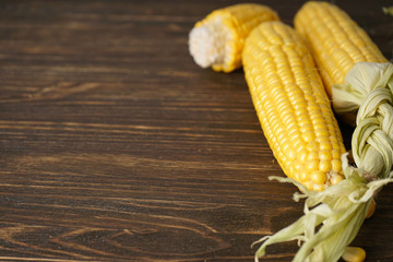 Ripe ears of corn on a wooden background. Space for text.